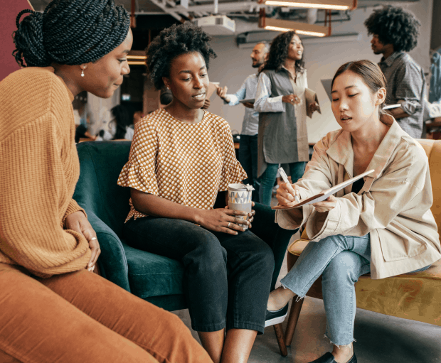 A group of women discussing a business proposal in an open-plan office.